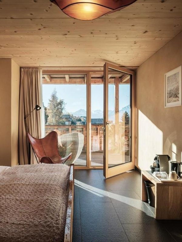 A guest room with a wooden ceiling and a balcony door open to the view