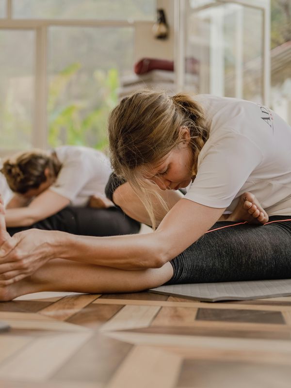Participants folding forward on their mats in a bright studio