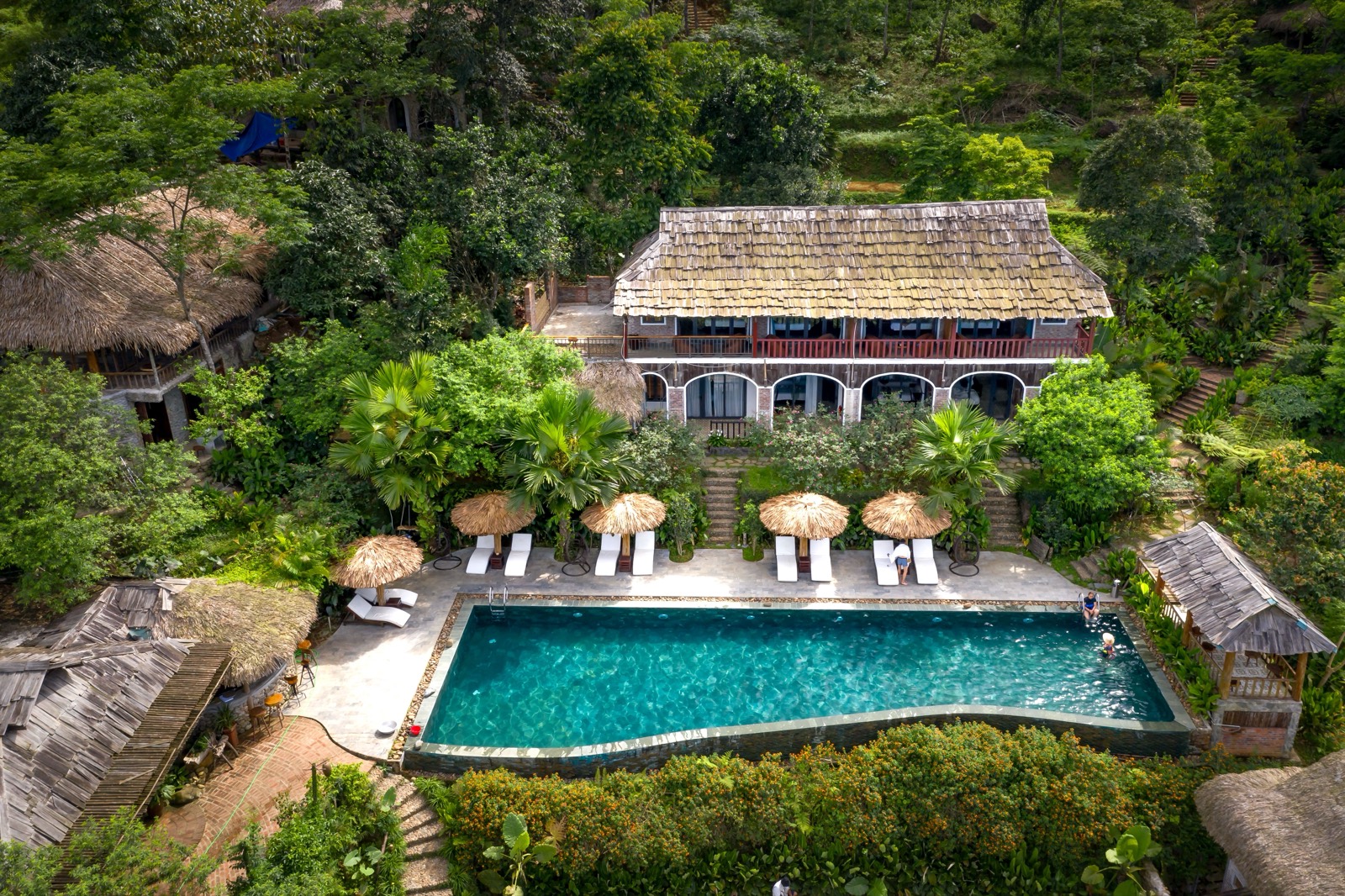 A retreat house with a pool, set among trees on a green hillside